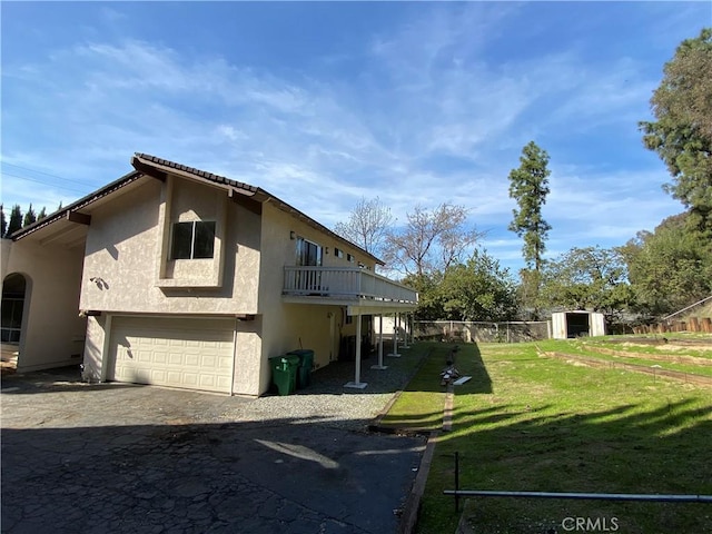 view of side of property with a balcony, a garage, and a lawn