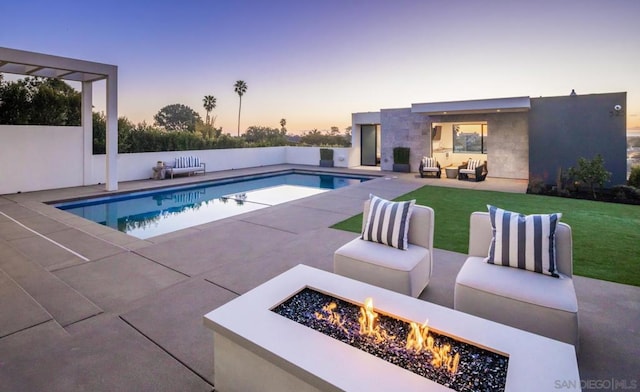 pool at dusk featuring a patio and an outdoor living space with a fire pit