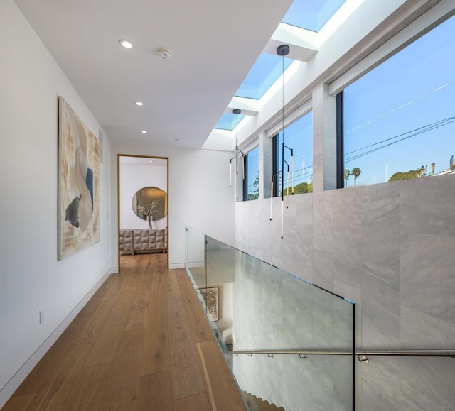 hallway with a skylight and hardwood / wood-style floors