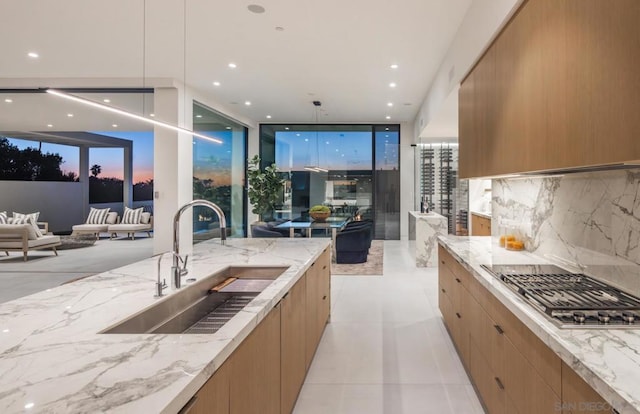 kitchen with sink, light tile patterned floors, light stone counters, tasteful backsplash, and stainless steel gas stovetop