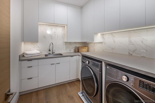 laundry room with cabinets, independent washer and dryer, light hardwood / wood-style floors, and sink