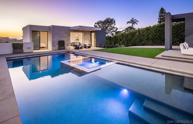 pool at dusk featuring a patio area, a lawn, and an in ground hot tub