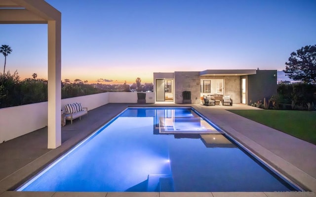 pool at dusk with a patio and outdoor lounge area