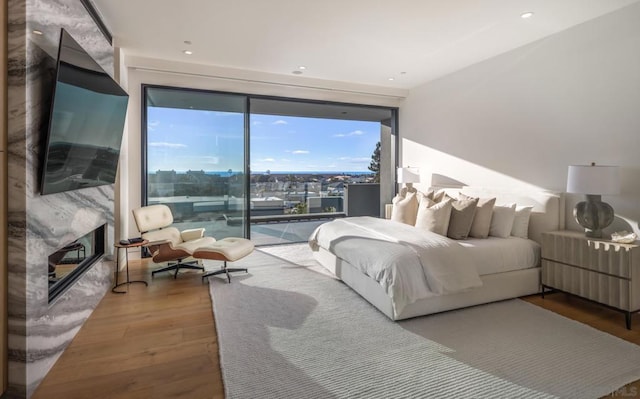 bedroom with wood-type flooring, access to exterior, and a high end fireplace