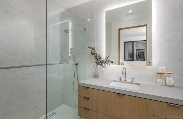 bathroom featuring vanity, tasteful backsplash, tile walls, and tiled shower