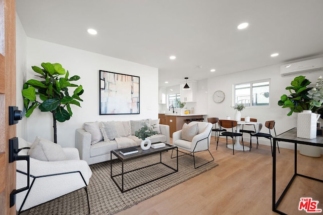 living room featuring sink, a wall mounted air conditioner, and light hardwood / wood-style floors