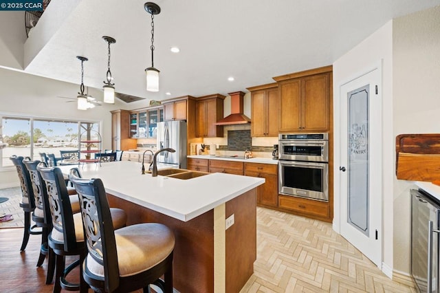 kitchen with sink, appliances with stainless steel finishes, a kitchen island with sink, wine cooler, and a kitchen bar