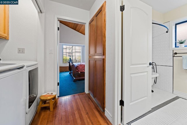 clothes washing area featuring dark hardwood / wood-style flooring, washer and clothes dryer, and cabinets