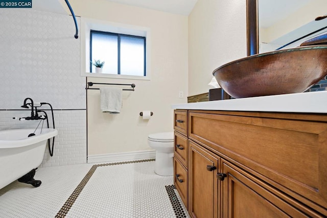 bathroom with tile walls, a bathing tub, vanity, tile patterned floors, and toilet