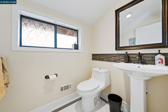 bathroom with tile patterned flooring, tasteful backsplash, toilet, and vaulted ceiling