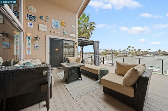 wooden terrace with an outdoor living space with a fire pit and a water view