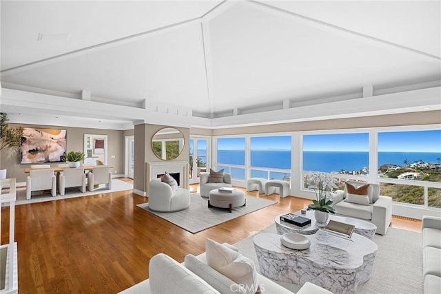 living room with a water view, high vaulted ceiling, and hardwood / wood-style flooring