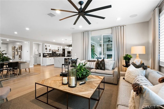 living room with ceiling fan, plenty of natural light, and light wood-type flooring