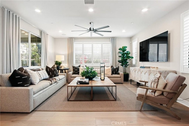 living room with ceiling fan, plenty of natural light, and light wood-type flooring