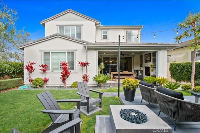 back of property with a fire pit, a patio area, and a lawn