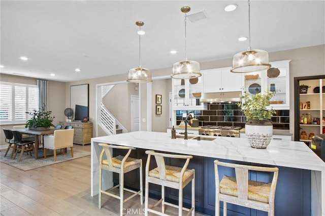 kitchen with white cabinetry, decorative light fixtures, decorative backsplash, and light wood-type flooring