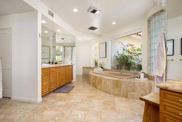 bathroom with tiled tub and vanity