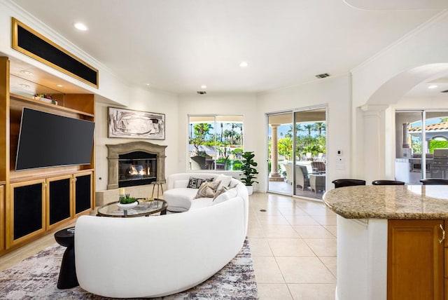 living room featuring light tile patterned floors, crown molding, and decorative columns