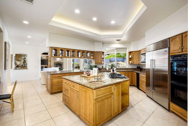 kitchen with a tray ceiling, kitchen peninsula, a kitchen island, and black appliances