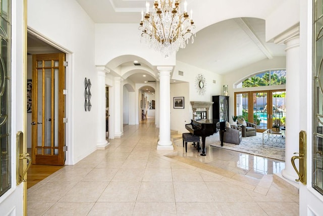 foyer featuring ornate columns, light tile patterned floors, high vaulted ceiling, and french doors