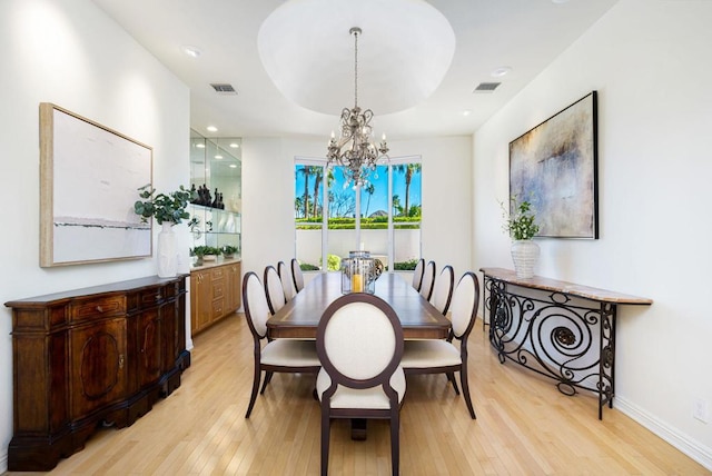 dining room featuring a tray ceiling, a chandelier, and light hardwood / wood-style floors