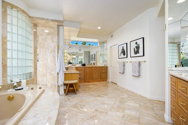 bathroom with vanity and a relaxing tiled tub