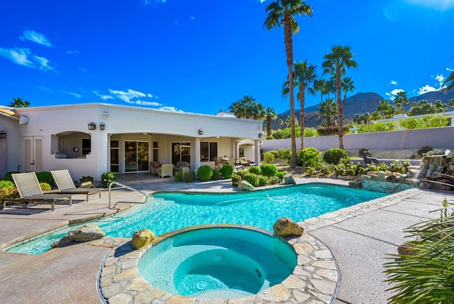 view of pool featuring an in ground hot tub, a mountain view, and a patio area