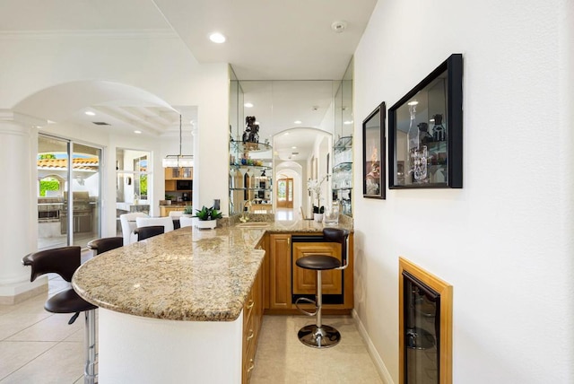 bar with light stone counters, beverage cooler, light tile patterned flooring, and sink