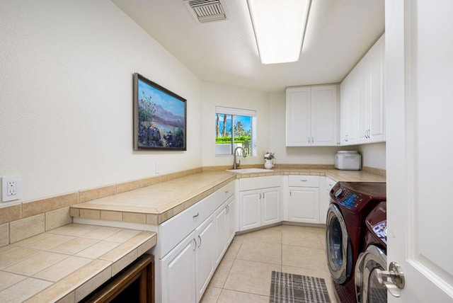 washroom with cabinets, sink, light tile patterned floors, and washer and clothes dryer