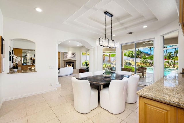 dining room featuring decorative columns, light tile patterned floors, and a tray ceiling