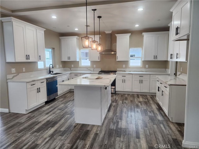 kitchen with appliances with stainless steel finishes, sink, white cabinets, a center island, and wall chimney exhaust hood