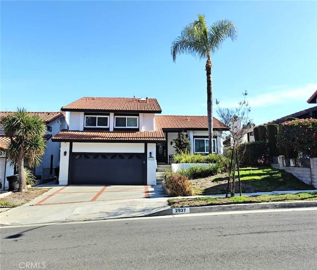 view of front of property featuring a garage, concrete driveway, a tile roof, and stucco siding