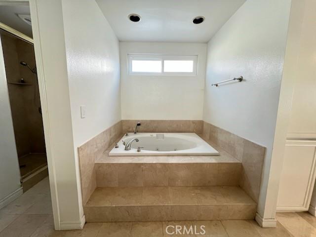 bathroom with a stall shower, a garden tub, and tile patterned floors