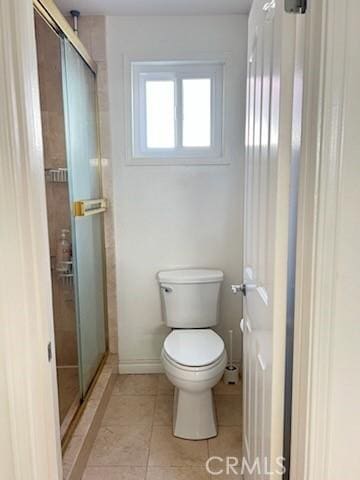 full bath with a stall shower, baseboards, toilet, and tile patterned flooring
