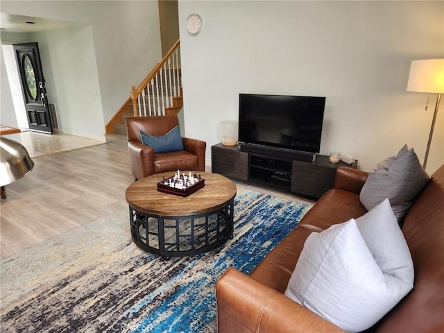 living room featuring stairway, baseboards, and wood finished floors