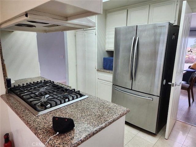 kitchen with light tile patterned floors, white cabinetry, custom range hood, and appliances with stainless steel finishes