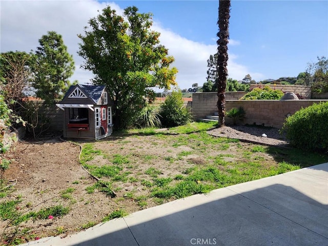 view of yard with a fenced backyard, a storage unit, and an outdoor structure