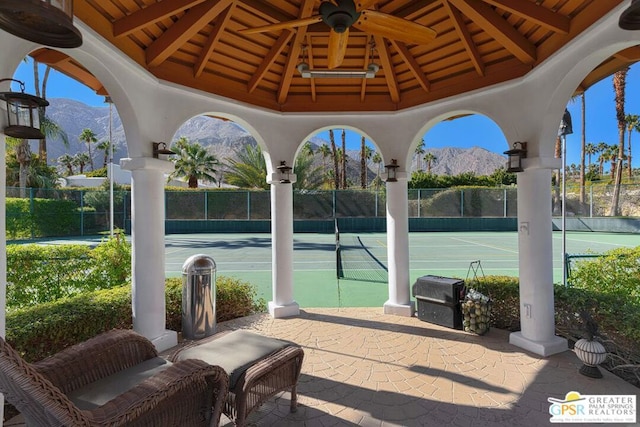 view of tennis court with a mountain view, a gazebo, and ceiling fan