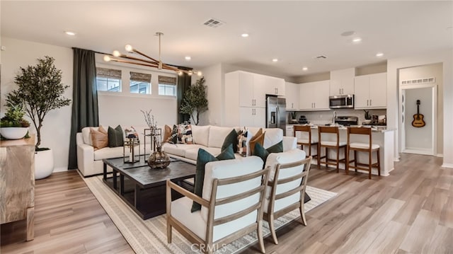 living room featuring an inviting chandelier and light hardwood / wood-style floors