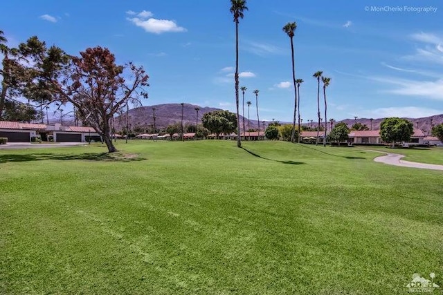 surrounding community with a mountain view and a lawn