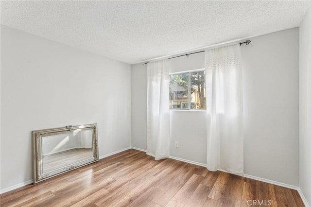 empty room with light hardwood / wood-style floors and a textured ceiling