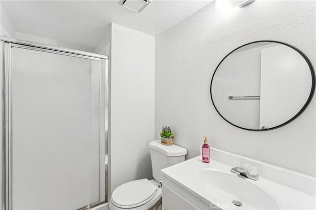 bathroom with vanity, toilet, and a shower with door