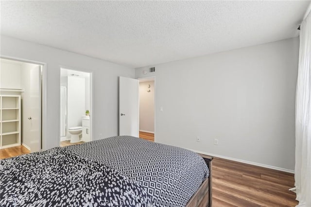 bedroom featuring connected bathroom, hardwood / wood-style floors, and a textured ceiling