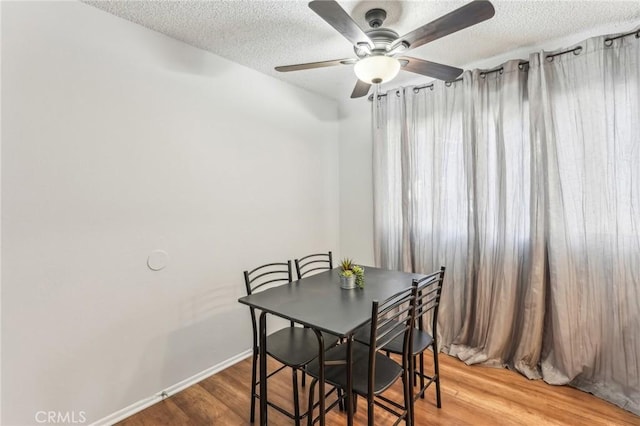 dining room with ceiling fan, wood-type flooring, and a textured ceiling