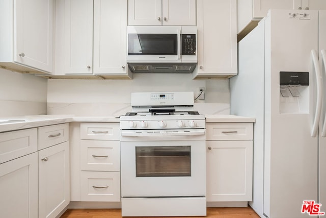 kitchen featuring white cabinetry, light stone countertops, light wood-type flooring, and white appliances