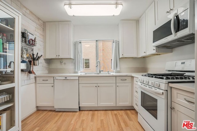 kitchen with white cabinetry, white appliances, sink, and light hardwood / wood-style flooring