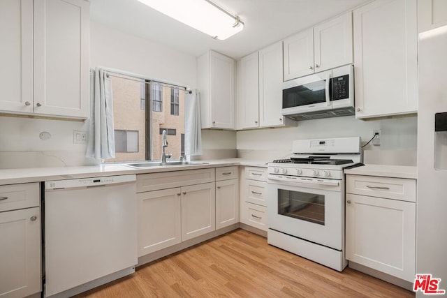 kitchen featuring sink, white cabinets, and white appliances