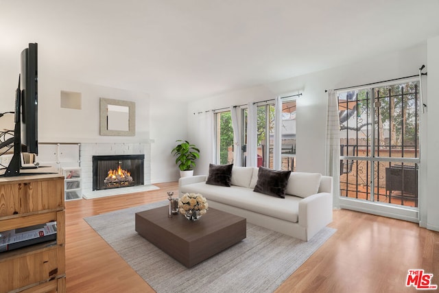 living room with a brick fireplace and light wood-type flooring