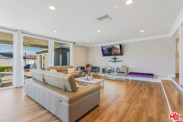 living room featuring crown molding and light hardwood / wood-style flooring