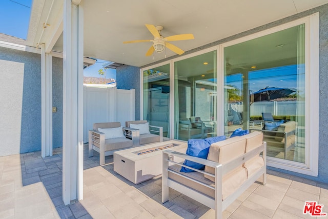 view of patio / terrace featuring ceiling fan and an outdoor living space with a fire pit